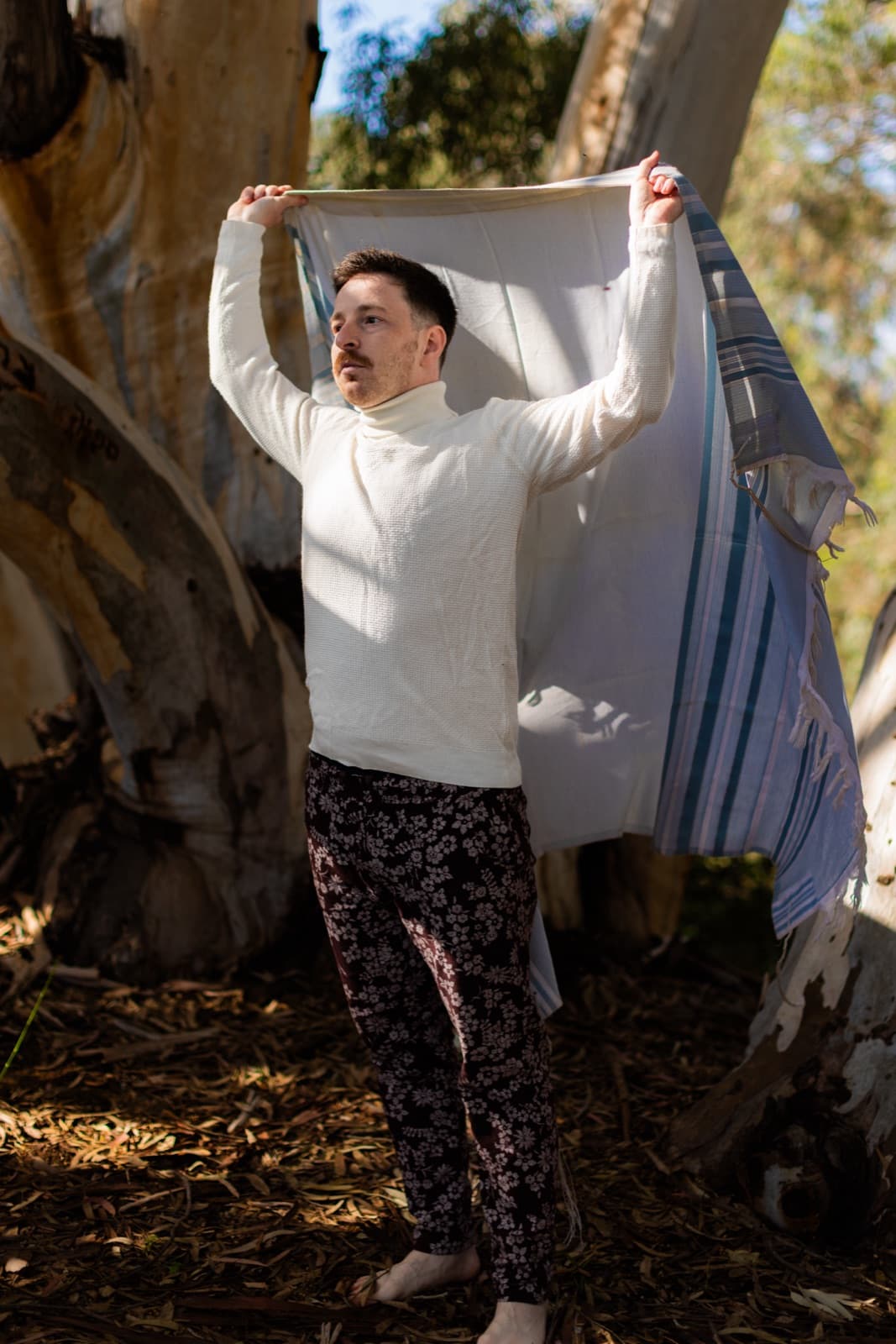 Eli Freedman holding a tallit between eucalyptus trees